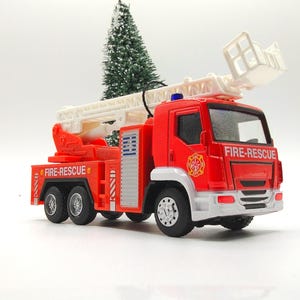 May include: A red toy fire truck with a white extending ladder. The truck has black wheels, a white cab, and the words "FIRE-RESCUE" printed on the side. The fire truck is a toy.