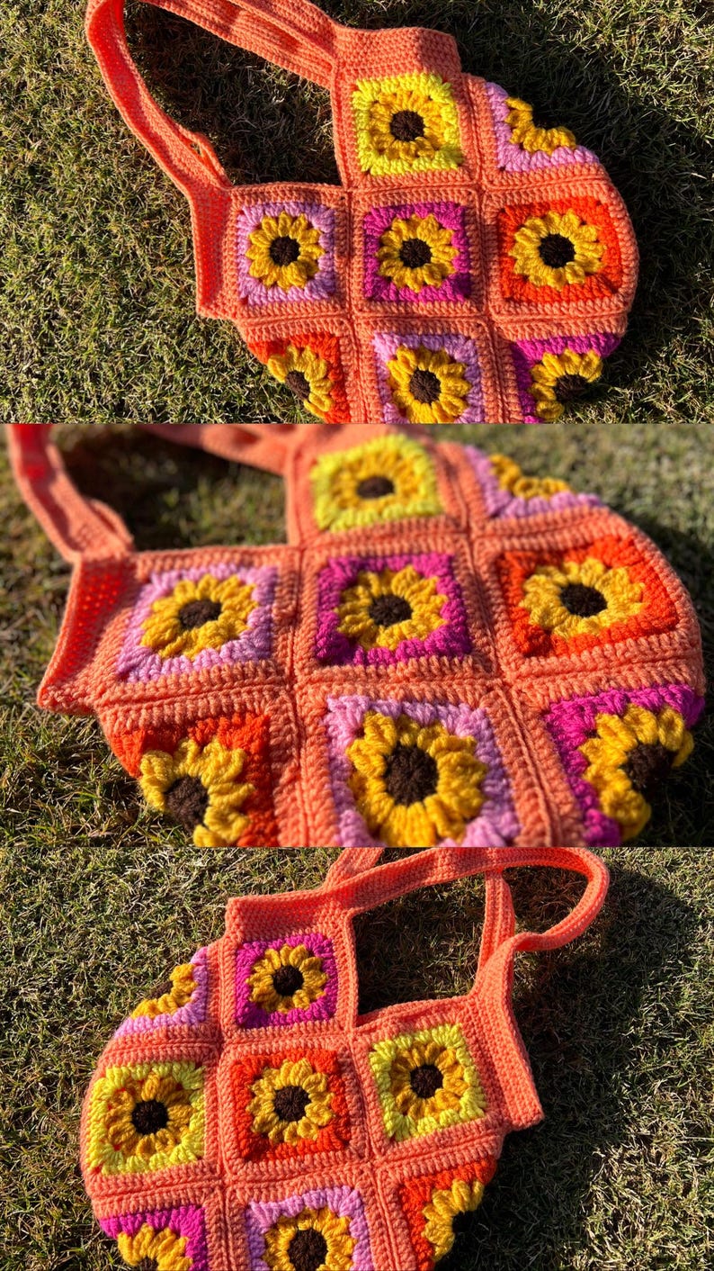 May include: A handmade crochet tote bag featuring a sunflower design. The bag is made of orange yarn with yellow, pink, and brown sunflower details. The bag has two handles and is sitting on green grass.