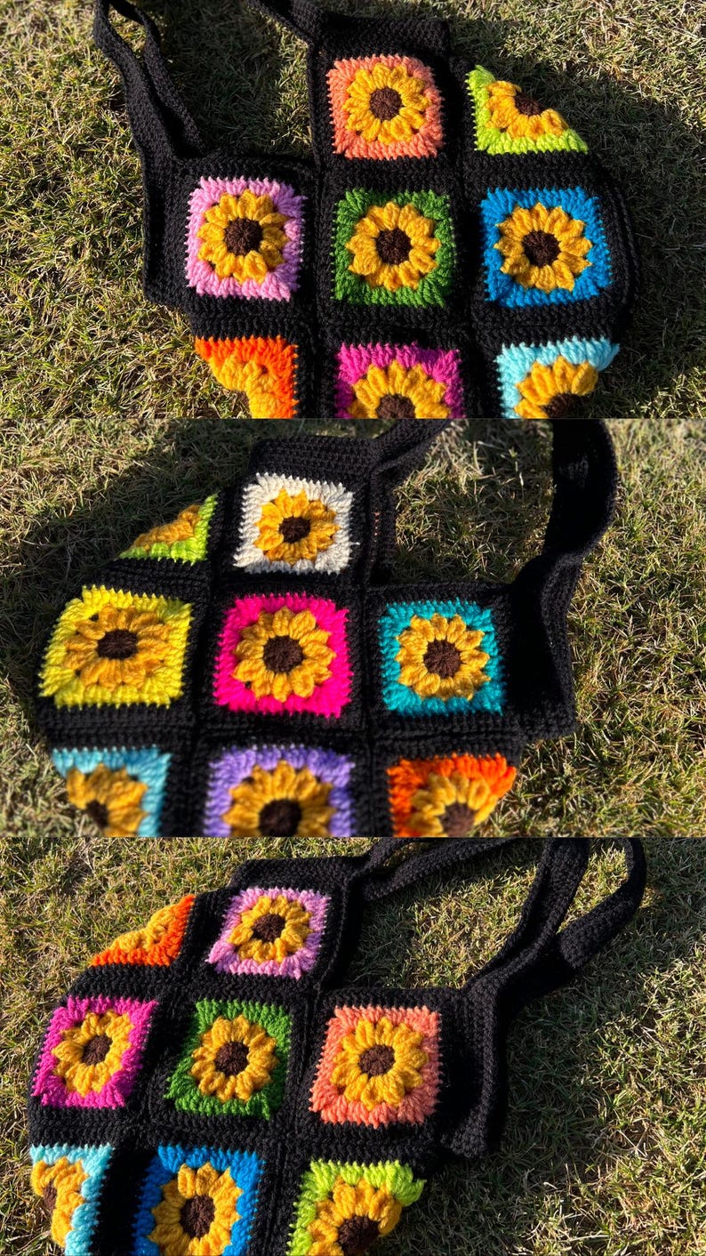 May include: Black crochet tote bag featuring colorful squares with sunflower designs. The sunflowers have yellow petals and brown centers, set against backgrounds of pink, green, blue, and orange. The bag has two black handles.