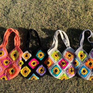 May include: Four handmade crochet tote bags with sunflower designs. Each bag features a different color scheme: orange, black, white, and gray. The bags are made with colorful squares and have matching handles.