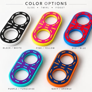 May include: Five oval-shaped fidget toys with two circular holes, each featuring a raised dash pattern. Color combinations include black and white, pink and yellow, red and blue, purple and turquoise, and navy and orange. Text reads COLOR OPTIONS.