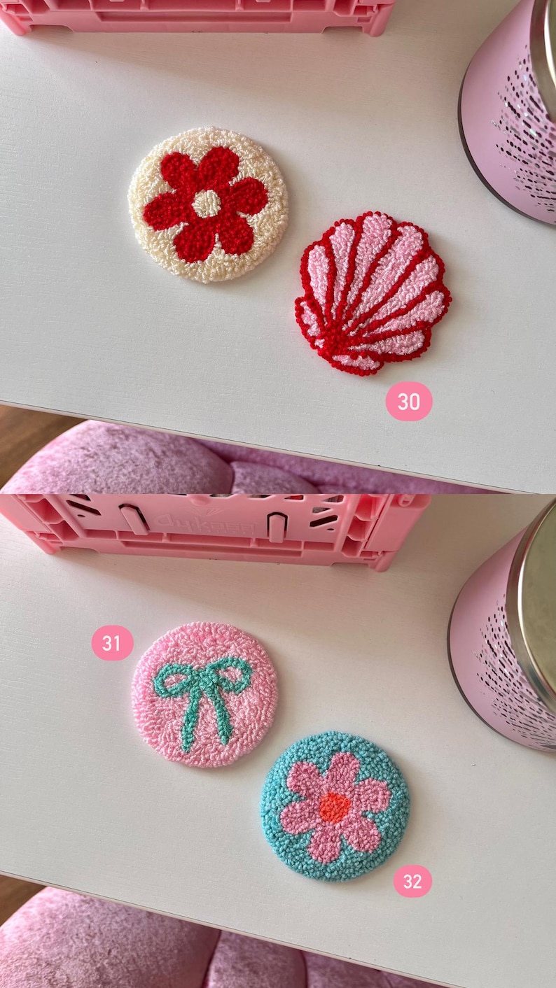 May include: A collection of colorful, embroidered coasters. Designs include a red flower on a cream background, a pink seashell, a pink bow, and a blue flower with a pink center. These decorative coasters are perfect for adding a touch of handmade charm to any home.