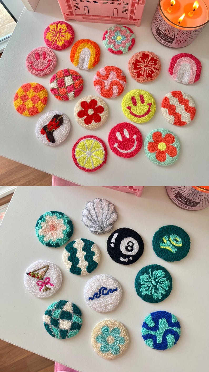 May include: A collection of colorful, round, hand-tufted coasters. Designs include smiley faces, rainbows, flowers, and geometric patterns. The coasters are made with various colors of yarn and are arranged on a white surface.