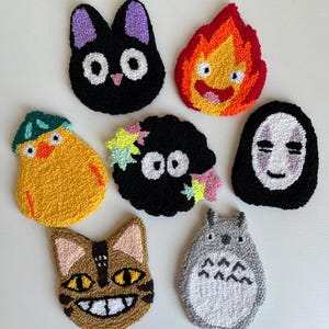 Puede incluir: Siete parches de personajes de fieltro de colores que representan personajes populares de las películas de animación del Studio Ghibli. Los parches incluyen Totoro, Sin Cara, el gato de Kiki Entregas a Domicilio, Calcifer y un pollito amarillo.