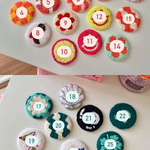 May include: A collection of 27 colorful, handmade, round coasters. Each coaster features a unique design, including floral patterns, stripes, and geometric shapes. The coasters are made with a textured, looped yarn and are arranged on a white surface.