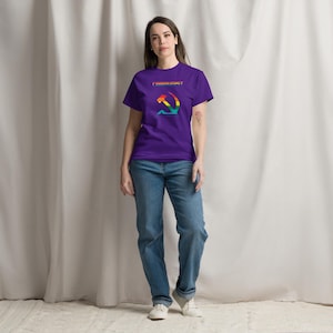 Puede incluir: Una camiseta morada con la palabra "COMMUNIST" sobre un diseño de martillo y hoz en arcoíris. La camiseta se combina con vaqueros azules y zapatillas blancas. El estilo general es informal y relajado.