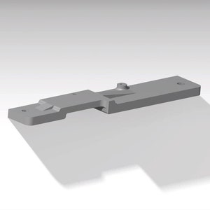 May include: A gray metal part with a rectangular shape and a small hole on the top. The part has a slight curve in the middle and a small protrusion on the side.