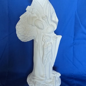 May include: White ceramic bunny figurine wearing a hat and holding a basket of carrots. The bunny is standing on a base with a leafy design.