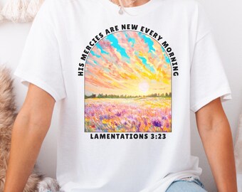 May include: White t-shirt with a colorful sunset and field of flowers graphic. The text "His mercies are new every morning" is in a semi-circle above the graphic. The text "Lamentations 3:23" is below the graphic.