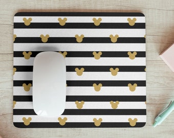 May include: A black and white striped mouse pad with gold Mickey Mouse ears. A white computer mouse is on the mouse pad.