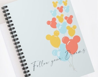 May include: A light blue spiral notebook with a white background and the text "Follow your Dreams" written in black cursive. The background features a cluster of colourful Mickey Mouse head balloons in shades of yellow, red, and blue.