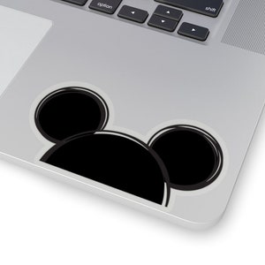 Op de afbeelding: Een zwart-witte Mickey Mouse-sticker op een zilveren laptop.