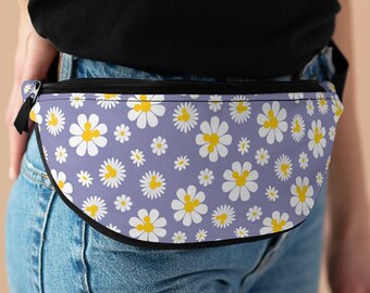 May include: A purple fanny pack with a white daisy pattern and yellow centers. The fanny pack is worn around the waist of a person wearing blue jeans.