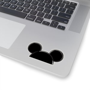 Op de afbeelding: Een zwart-witte sticker van Mickey Mouse's hoofd met grote oren. De sticker zit op een zilveren laptop.