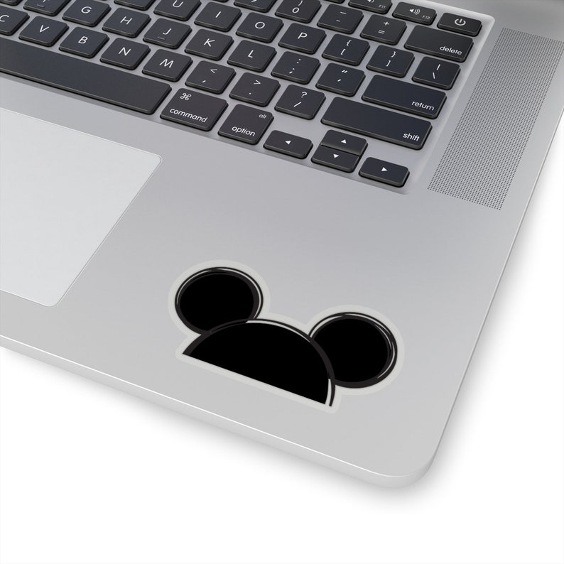 Op de afbeelding: Een zwart-witte sticker van Mickey Mouse's hoofd met grote oren. De sticker zit op een zilveren laptop.