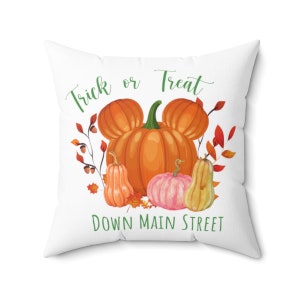 Puede incluir: Almohada blanca con un dise&ntilde;o de calabazas verdes, naranjas y rosas. El texto "Trick or Treat Down Main Street" est&aacute; impreso en la almohada.