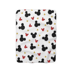 K&ouml;nnte beinhalten: Wei&szlig;e Fleece-Decke mit einem sich wiederholenden Muster aus schwarzen Mickey-Maus-K&ouml;pfen und kleinen roten und gelben Mickey-Maus-K&ouml;pfen.