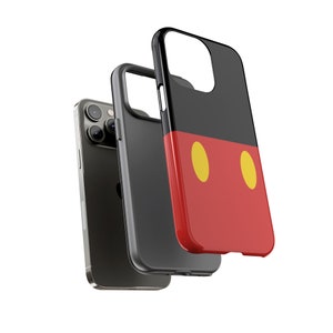 以下が含まれることがあります： 赤と黒のミッキーマウスのデザインが施された黒い携帯電話ケース。ケースの赤い部分に黄色の円が2つあります。