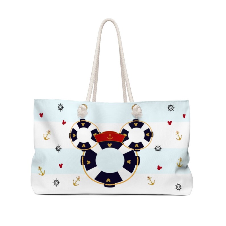 K&ouml;nnte beinhalten: Eine wei&szlig;e Canvas-Tragetasche mit blau-wei&szlig;em Streifenmuster. Die Tasche zeigt eine Mickey-Maus-Silhouette aus Rettungsringen mit einem roten Kapit&auml;nshut. Die Tasche ist mit Ankern, Herzen und Schiffsr&auml;dern verziert.