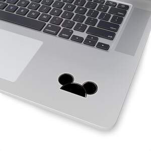 Op de afbeelding: Zwart-witte sticker van Mickey Mouse's hoofd met grote oren op een zilveren laptop.