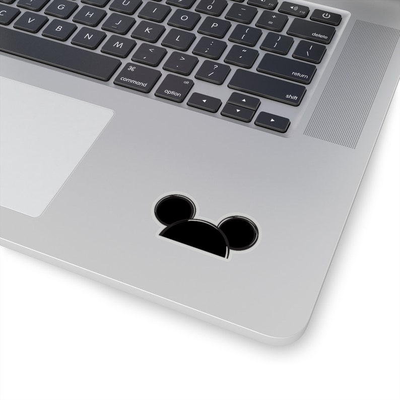 Op de afbeelding: Zwart-witte sticker van Mickey Mouse's hoofd met grote oren op een zilveren laptop.