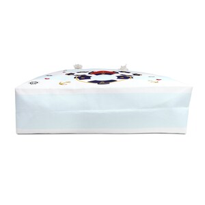 K&ouml;nnte beinhalten: Eine wei&szlig;e Canvas-Tragetasche mit einem blau-roten nautischen Design. Das Design zeigt einen Rettungsring, Anker und ein Steuerrad.