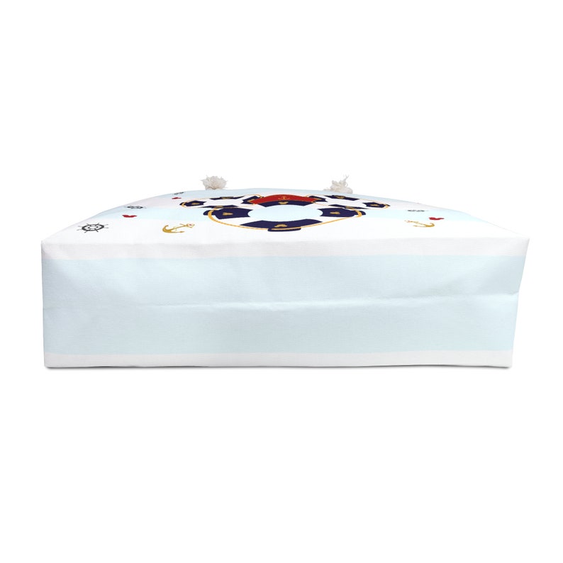 K&ouml;nnte beinhalten: Eine wei&szlig;e Canvas-Tragetasche mit einem blau-roten nautischen Design. Das Design zeigt einen Rettungsring, Anker und ein Steuerrad.