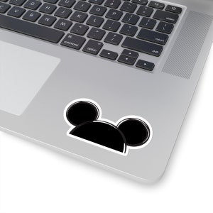 Op de afbeelding: Zwart-witte sticker van Mickey Mouse oren op een zilveren laptop.