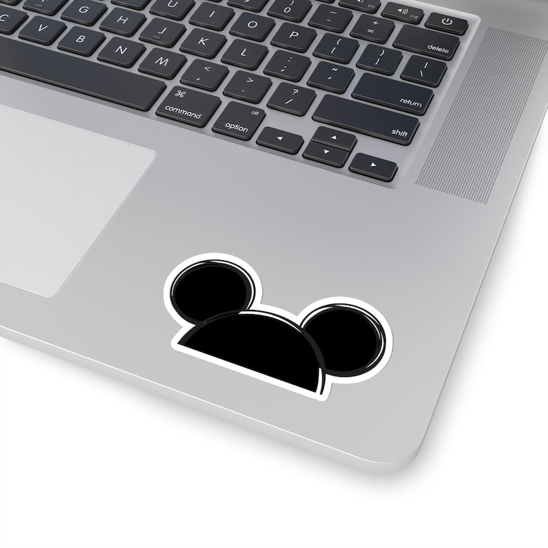 Op de afbeelding: Zwart-witte sticker van Mickey Mouse oren op een zilveren laptop.
