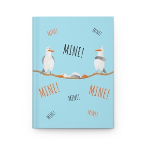 Peut inclure: Une couverture de carnet bleu clair avec une illustration de trois mouettes sur une corde. Les mouettes disent "MINE!" en texte orange.