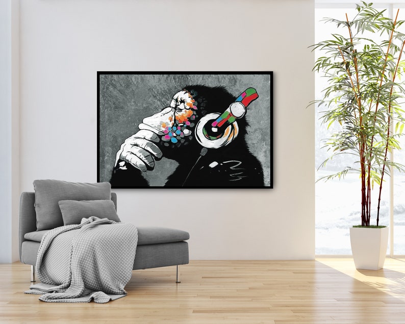May include: A black and white illustration of a monkey wearing colorful headphones. The monkey is sitting with its chin on its hand, looking thoughtful. The background is a gray, textured surface.