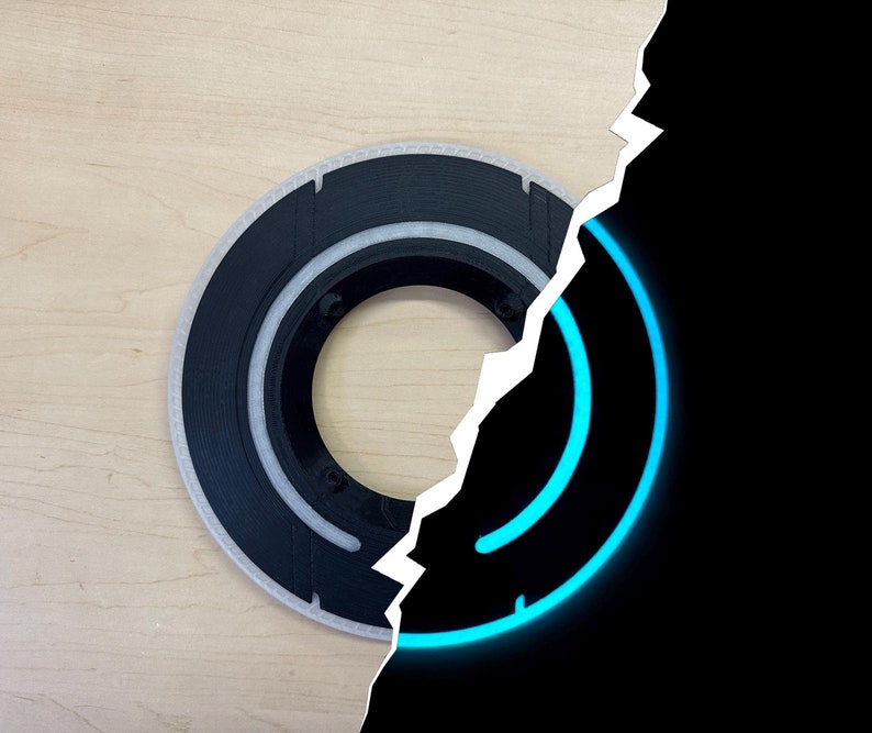 May include: A circular black and white object with a series of concentric rings. The object is partially illuminated by a bright blue glowing ring on a black background. The object is on a light wood surface.