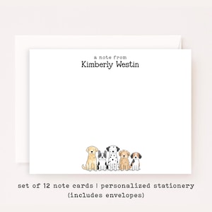 May include: A white note card with the black printed text a note from Kimberly Westin at the top and a colorful watercolor illustration of five different dog breeds sitting in a row at the bottom, accompanied by a matching white envelope.