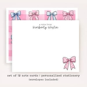 May include: A set of white note cards featuring the black printed text a note from Kimberly Westin. The cards display a pink and white checkered pattern with various blue and pink bows, including a single pink polka dot bow in the corner.