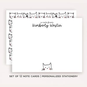 May include: A set of white note cards featuring a black and white cat illustration border and a single cat at the bottom. The text reads a note from Kimberly Westin in black script. The stationery set includes twelve cards for personal correspondence.