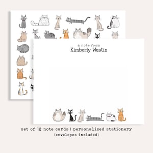 May include: A set of white note cards featuring a variety of illustrated cats in different colors and patterns. The front of the card displays the text a note from Kimberly Westin in black font, with a row of cartoon cats along the bottom edge.