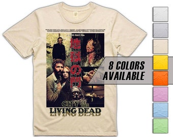Puede incluir: Una camiseta beige con un diseño de póster de película vintage que incluye el texto "City of the Living Dead" y caracteres japoneses. El póster presenta una escena de la película con un grupo de personas en un área boscosa oscura. La camiseta está disponible en 8 colores.