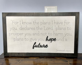 May include: A framed wood sign with a white background and black text. The text reads "For I know the plans I have for you." declares the Lord, "plans to prosper you and not to harm you, plans to give you hope and a future." Jeremiah 29:11