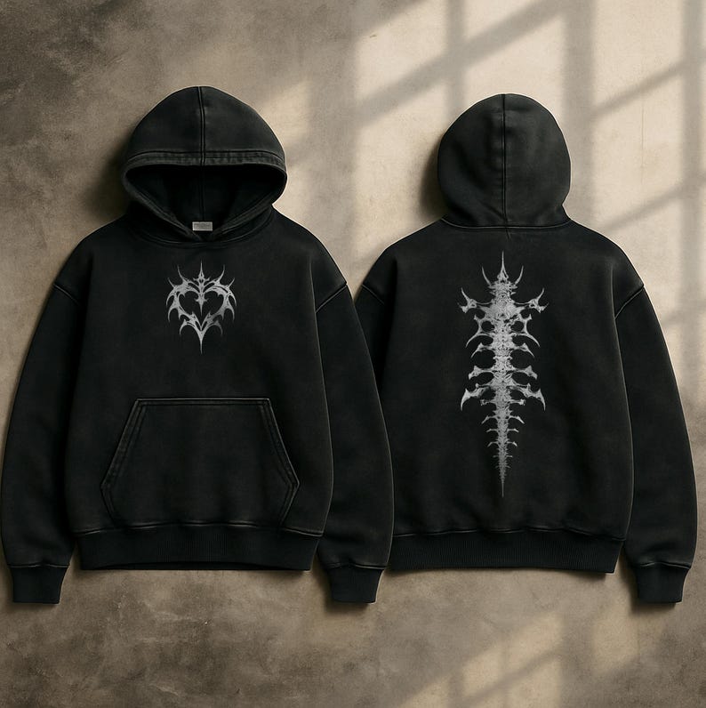 Op de afbeelding: Zwarte hoodie met een voorzak en capuchon. De voorkant heeft een zilverkleurig hartvormig ontwerp, terwijl de achterkant een ruggengraatachtige afbeelding toont. De hoodie is gemaakt van een zacht, comfortabel materiaal.