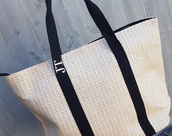 May include: A large, white woven tote bag with black straps. The bag has the initials "JT" printed on the front.
