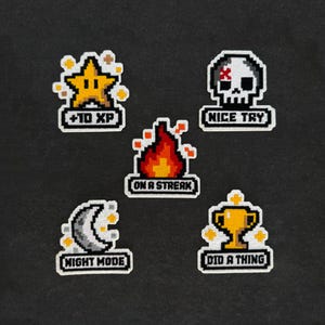 May include: Five pixel art embroidered patches featuring a yellow star with +10 XP, a white skull with NICE TRY, a red and orange flame with ON A STREAK, a gray crescent moon with NIGHT MODE, and a gold trophy with DID A THING.