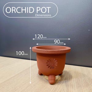 May include: Terracotta orchid pot with three legs and a decorative cutout design. The pot measures 120mm wide, 90mm deep, and 100mm high.