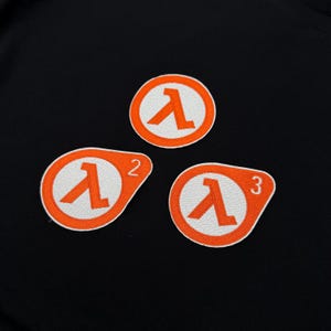 May include: Three orange and white embroidered patches featuring the lambda symbol. Two patches have the numbers 2 and 3. The patches are circular and oval-shaped, with a white lambda symbol inside an orange circle.