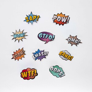Può includere: Una collezione di toppe colorate in stile fumetto con varie esclamazioni. Le toppe presentano parole come "ZAP!", "POW!", "WOW!", "GTFO!", "OMG!", "BOOM!", "SMASH!", "BANG!", "OOPS!" e "WTF!" in caratteri grassi e stilizzati.