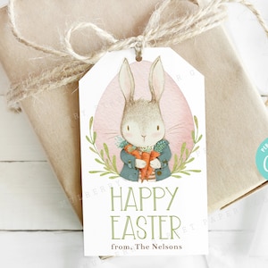 May include: A white gift tag with a watercolor illustration of a bunny holding a carrot. The bunny is wearing a blue jacket and a red scarf. The tag has the text "Happy Easter" and "from. The Nelsons" in green text.