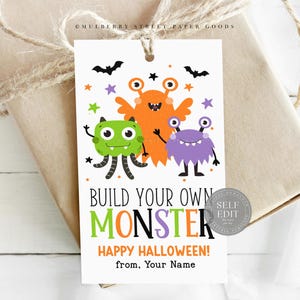 May include: A white tag with a Halloween theme, featuring three cartoon monsters in orange, green, and purple. The tag reads "Build Your Own Monster" and "Happy Halloween!" with a space for a name. Black bats and stars decorate the top.