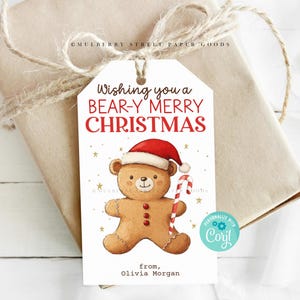 Könnte beinhalten: Weißer Geschenkanhänger mit einem Lebkuchenbär, der einen Weihnachtsmann-Hut trägt und einen Zuckerstock hält. Der Anhänger lautet "Wishing you a BEAR-Y MERRY CHRISTMAS" und "from, Olivia Morgan".