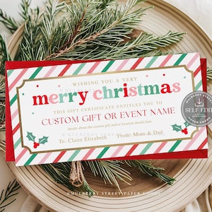 May include: A Christmas gift certificate with a red border and diagonal stripes in red, green, and pink. The text "merry christmas" is in red and green. The certificate is on a wooden plate with greenery.