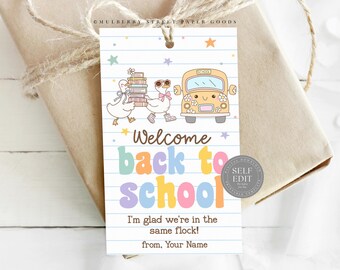 May include: A gift tag with a school theme. The tag features a yellow school bus and two cartoon geese carrying books. Text on the tag reads "Welcome back to school" and "I'm glad we're in the same flock!"