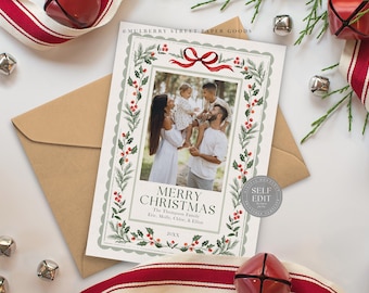 May include: A Christmas card with a family photo, framed by a green and red botanical border. The card features the text "Merry Christmas" and the family's name. A red ribbon and envelope are visible.
